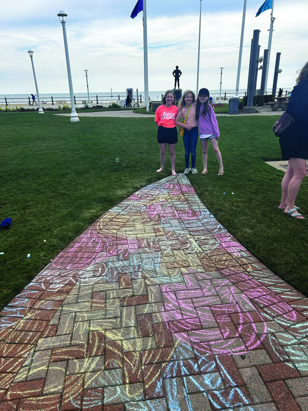 Quinn, Calanit and Grayce pose with their chalk art before the beach cleanup.