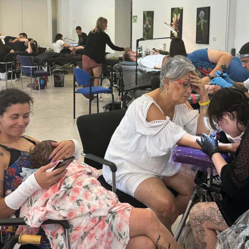 Two women receive tattoos.