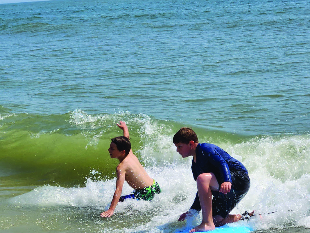 Ben Hollander and Micah Kass finish riding a wave while surfing with Sababa Beachaway