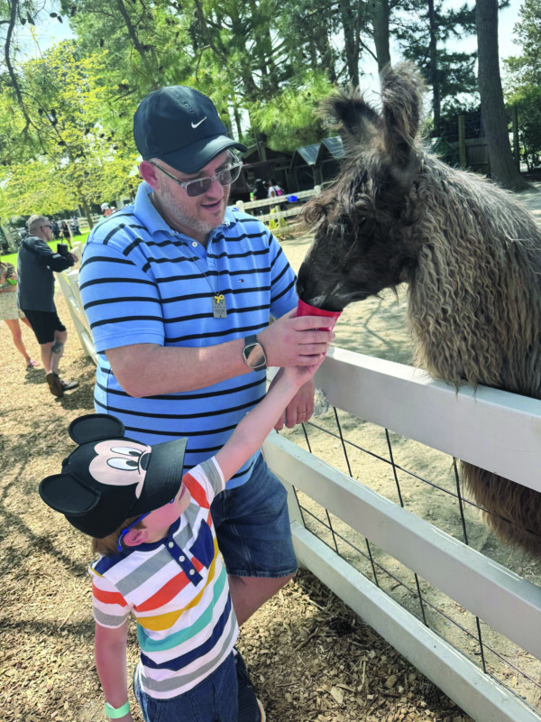 Rabbi Ari and Ben Oliszewski feed the alpaca.