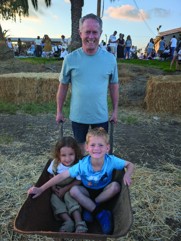 Shai Rubin (bottom right) participates in a wheelbarrow race as part of a Shavuot celebration on a moshav in Be’er Tuvia. Shikma Rubin’s uncle, Dror Barlev, pushes the wheelbarrow while Shai’s cousin, Tomer Vine, is along for the ride.