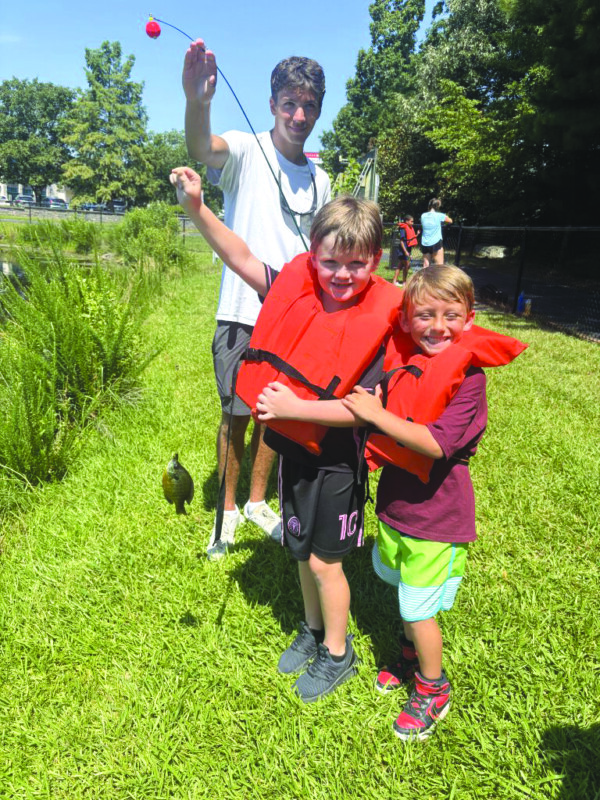 Bryon Johnson, Carter Lipton, and their counselor Mr. Jack (Poorman) reel in fish and fun at Lake Sandler. 