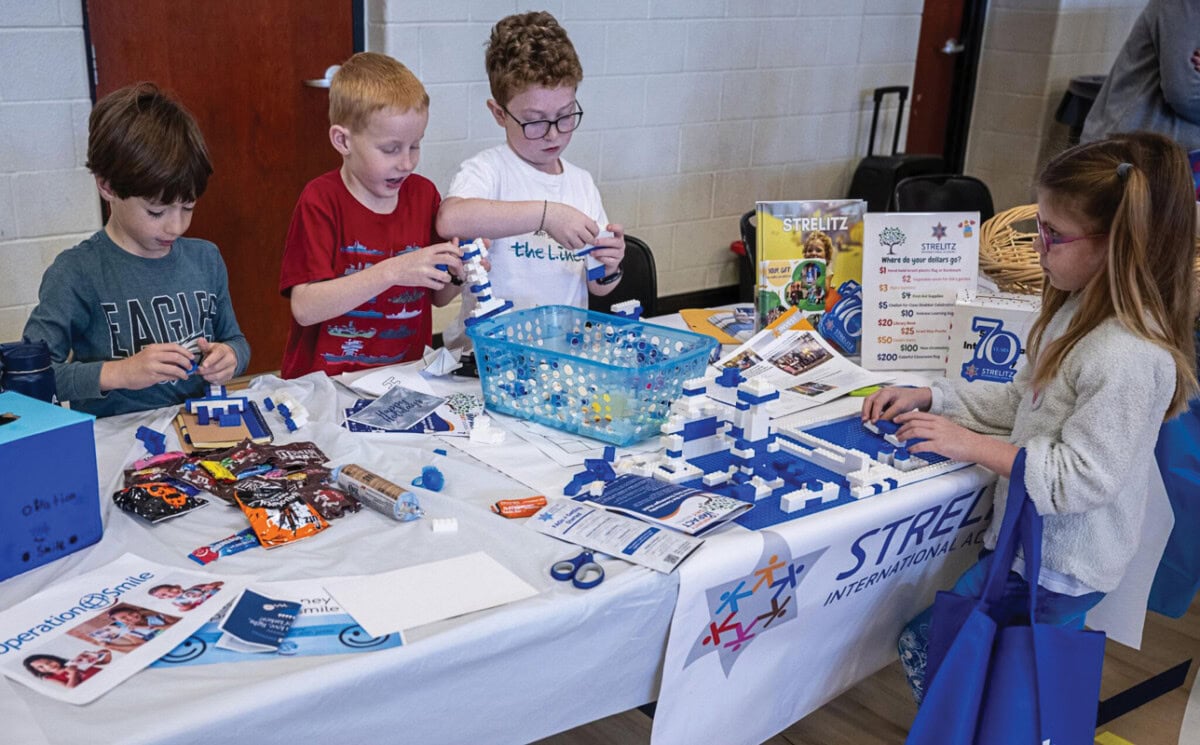 Johnny Aftel, Zachary Kingsland, Asher Mulligan, and Lia Oliszewski work together to build Lego structures at the Strelitz table