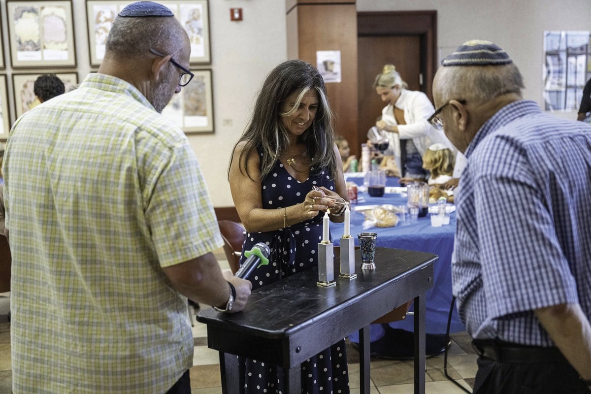 Pati Oliszewski lights the candles with Rabbi Ari and Rabbi Israel Zoberman.